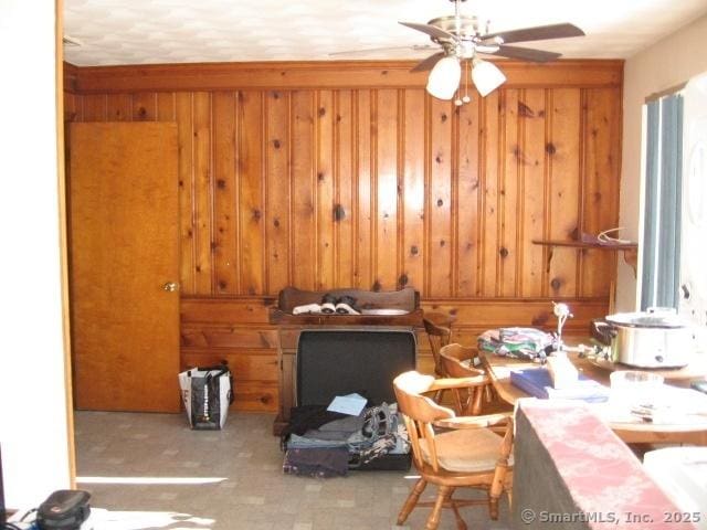 interior space with ceiling fan and wooden walls