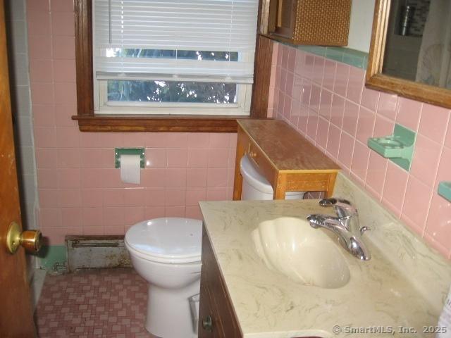 38 New Haven Rd, Seymour, CT 06483 - bathroom with vanity, toilet, tasteful backsplash, tile walls, and a baseboard heating unit