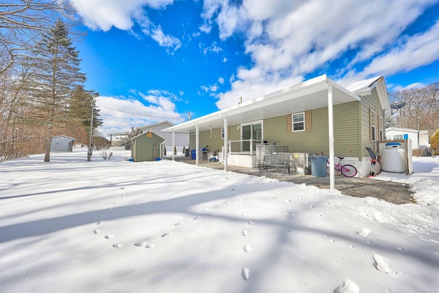 snow covered rear of property with a storage shed