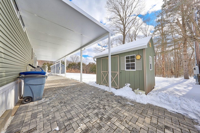 snow covered patio with a storage unit