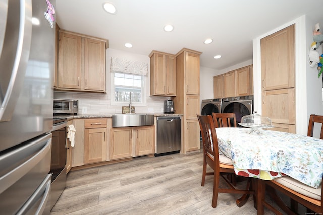 kitchen featuring sink, stainless steel appliances, washing machine and dryer, light brown cabinetry, and decorative backsplash