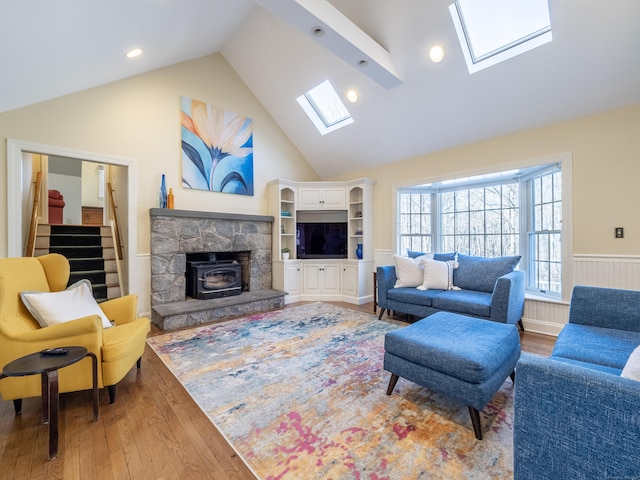 living room featuring a skylight, high vaulted ceiling, and wood-type flooring