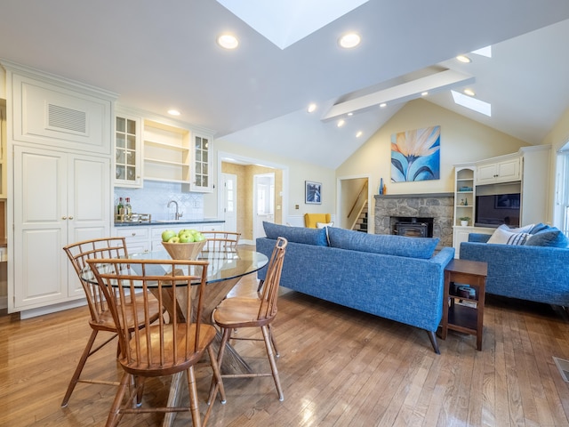 interior space featuring vaulted ceiling with skylight, sink, and light wood-type flooring