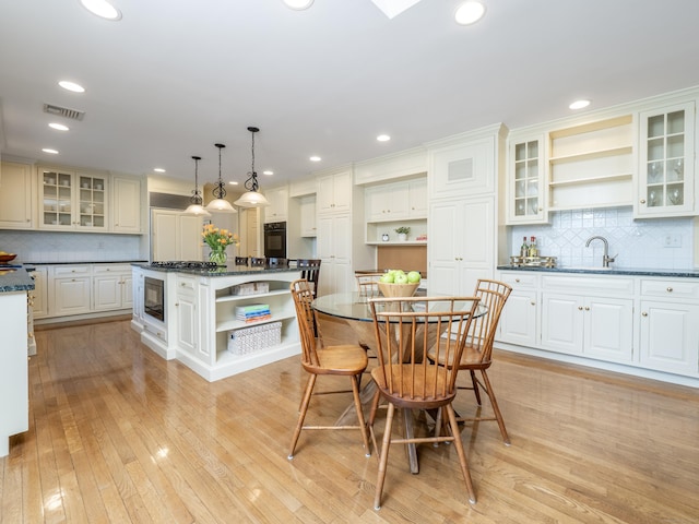 kitchen with decorative light fixtures, dark stone countertops, white cabinets, a center island, and black appliances