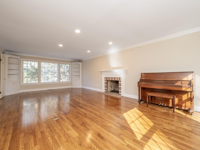 unfurnished living room with ornamental molding, a brick fireplace, and light hardwood / wood-style flooring