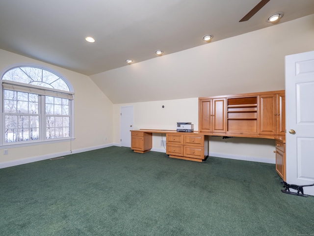 interior space with built in desk, dark colored carpet, ceiling fan, and vaulted ceiling