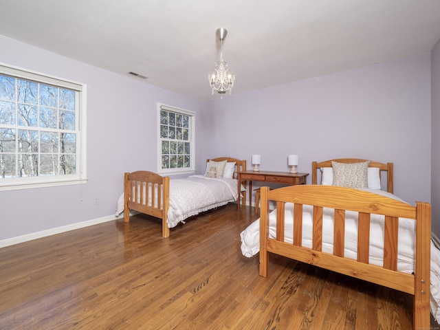 bedroom with dark hardwood / wood-style flooring and a notable chandelier