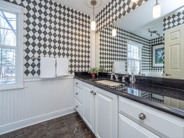 kitchen featuring dark stone countertops, sink, decorative light fixtures, and white cabinets