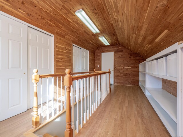 hall featuring vaulted ceiling, wooden walls, wooden ceiling, and light hardwood / wood-style floors