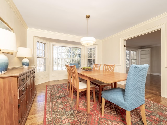 dining room with crown molding and light hardwood / wood-style flooring