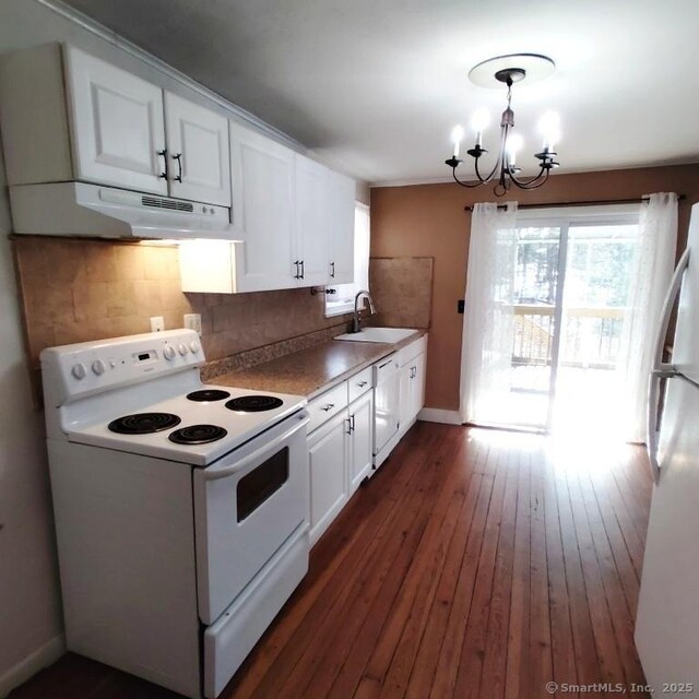 kitchen featuring sink, white appliances, tasteful backsplash, white cabinets, and decorative light fixtures