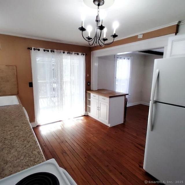 kitchen with pendant lighting, dark hardwood / wood-style floors, white refrigerator, white cabinets, and a chandelier