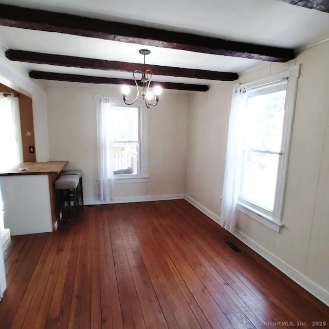 unfurnished dining area with a wealth of natural light, dark wood-type flooring, and beamed ceiling