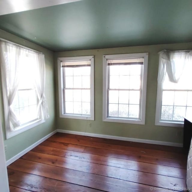 unfurnished room featuring a healthy amount of sunlight and dark hardwood / wood-style flooring