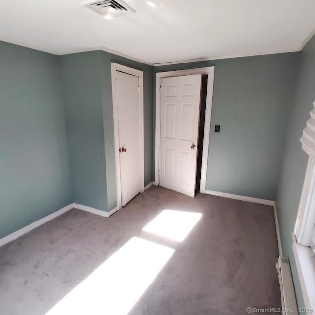 unfurnished bedroom with carpet floors and a baseboard heating unit