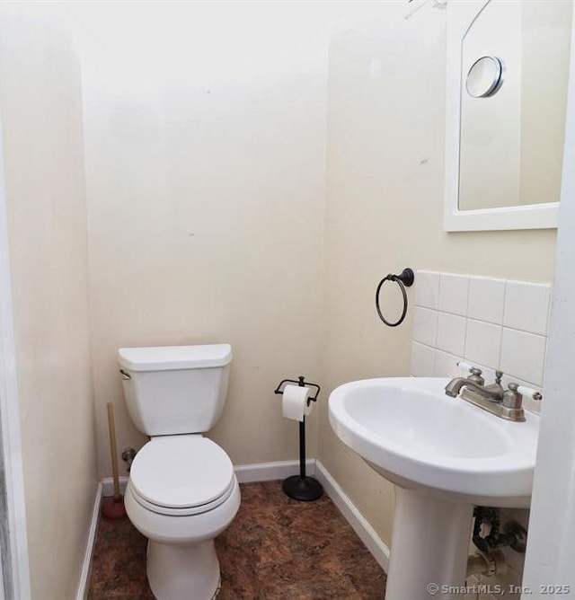 bathroom featuring tasteful backsplash, toilet, and sink