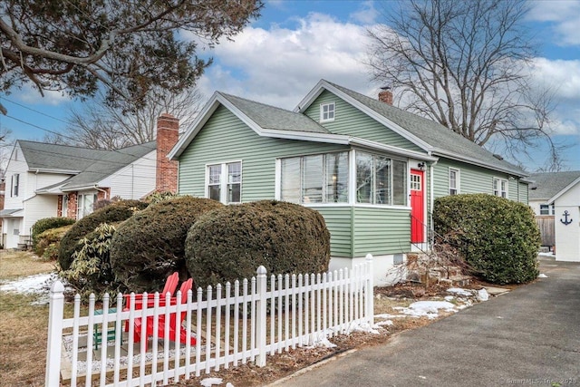 bungalow-style house featuring a chimney, fence, and roof with shingles