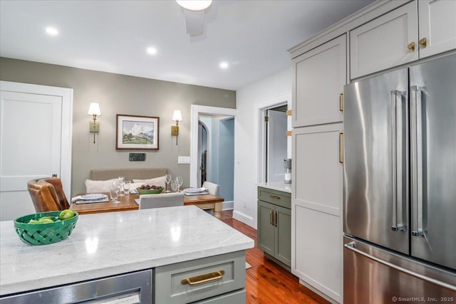 kitchen with light stone counters, gray cabinets, high end refrigerator, and dark hardwood / wood-style floors