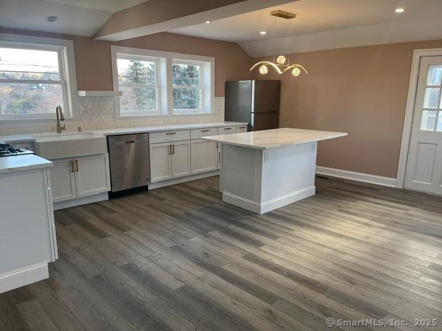 kitchen featuring pendant lighting, sink, appliances with stainless steel finishes, white cabinets, and a kitchen island