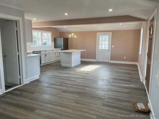 kitchen with white cabinetry, a kitchen island, stainless steel fridge, and lofted ceiling