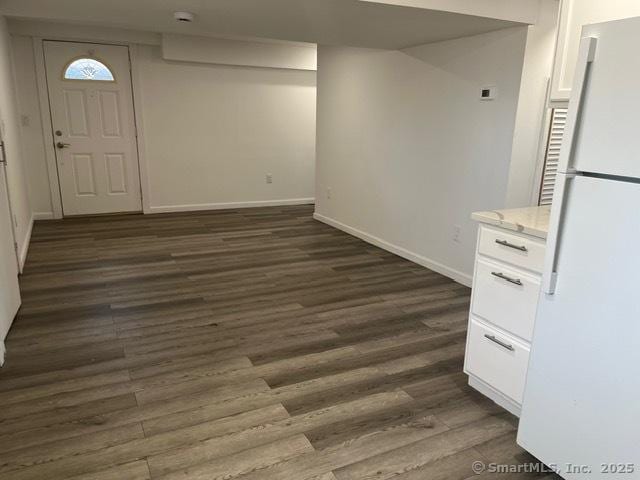 basement with white refrigerator and dark hardwood / wood-style flooring