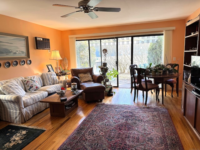 living room featuring a wall mounted air conditioner, plenty of natural light, ceiling fan, and light wood-type flooring