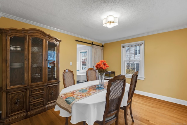 dining room with crown molding, a barn door, a textured ceiling, and light wood-type flooring