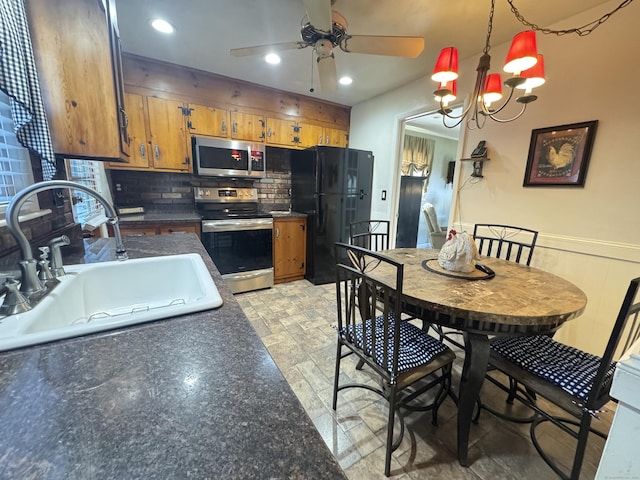 kitchen featuring sink, decorative light fixtures, stainless steel appliances, ceiling fan with notable chandelier, and backsplash