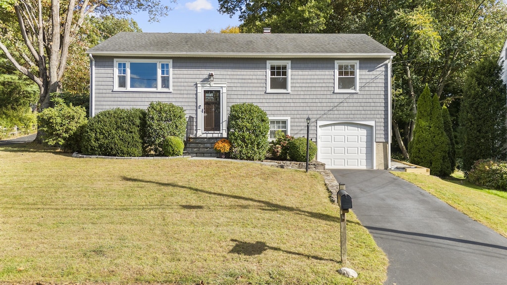 bi-level home featuring a garage and a front lawn