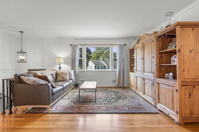 living room with crown molding, light hardwood / wood-style floors, and a notable chandelier