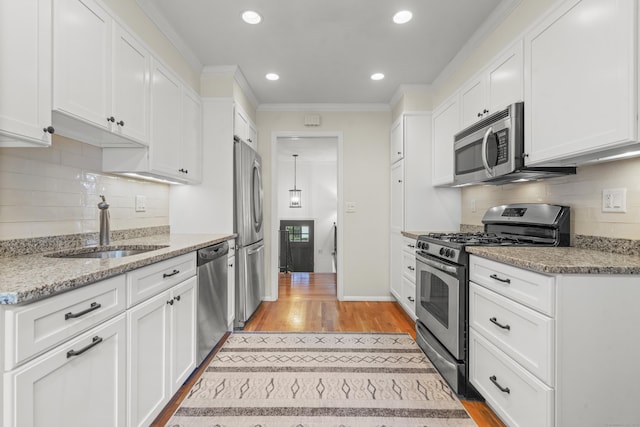 kitchen with light stone counters, sink, white cabinets, and appliances with stainless steel finishes