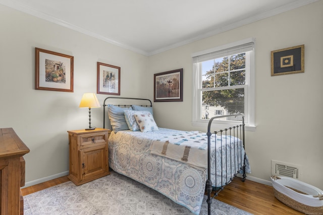 bedroom with ornamental molding and light hardwood / wood-style floors