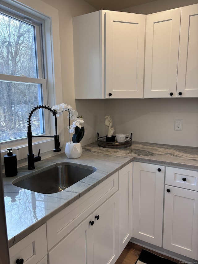 kitchen featuring white cabinetry, light stone countertops, and sink