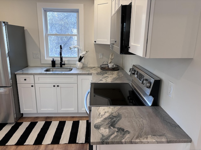 kitchen with appliances with stainless steel finishes, light stone countertops, sink, and white cabinets