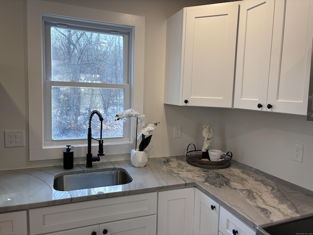 kitchen featuring white cabinetry, sink, and light stone countertops