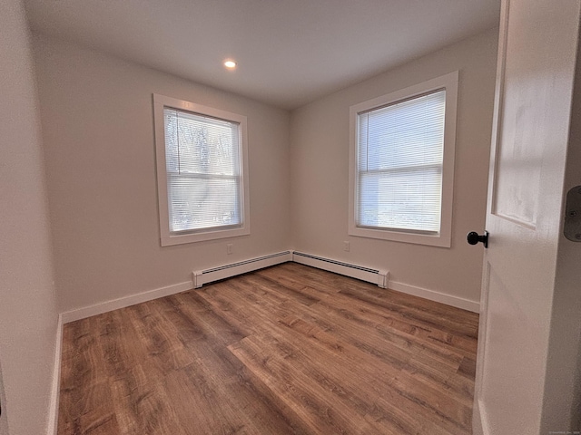 empty room featuring hardwood / wood-style flooring and a baseboard radiator