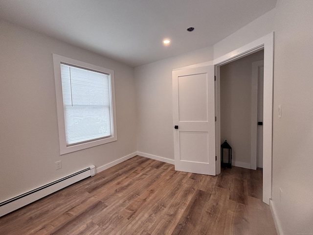 empty room featuring a baseboard heating unit and hardwood / wood-style floors