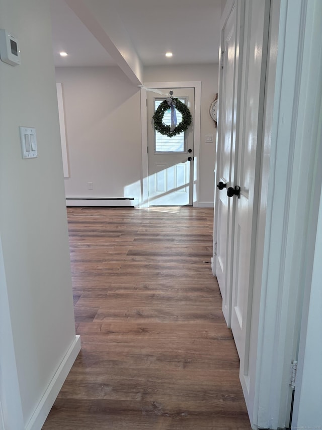 corridor featuring dark wood-type flooring and baseboard heating