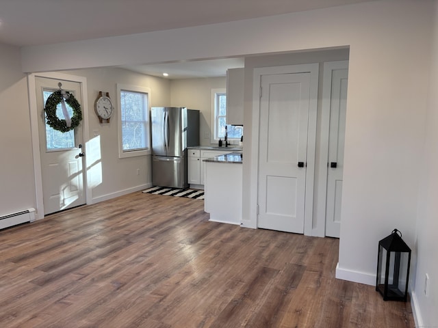 foyer entrance with sink, dark wood-type flooring, and a baseboard heating unit