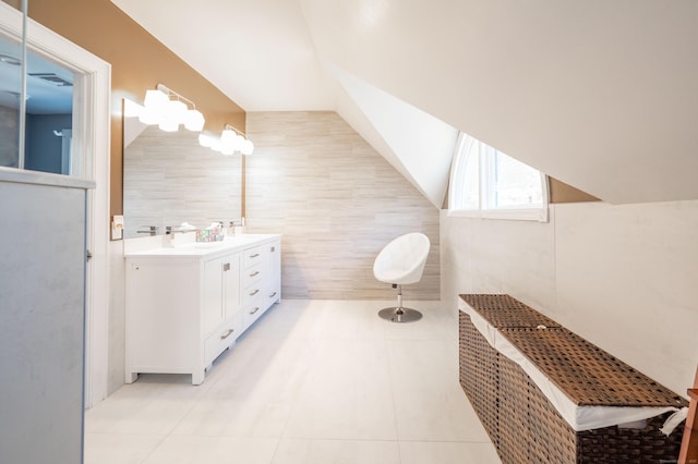 bathroom with tile walls, vanity, tile patterned flooring, and vaulted ceiling