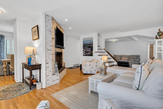 living room featuring a brick fireplace and light hardwood / wood-style floors