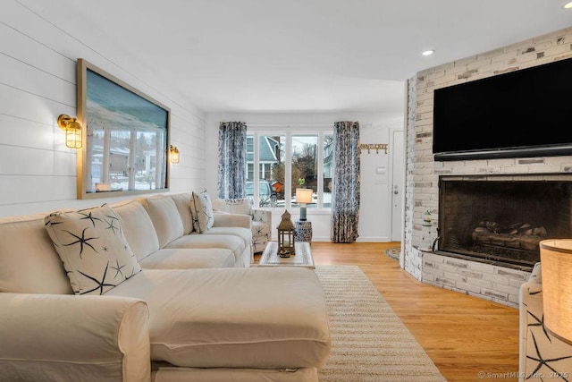 living room featuring a brick fireplace and light wood-type flooring