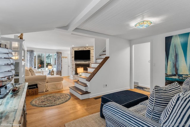 living room featuring lofted ceiling with beams and light hardwood / wood-style floors