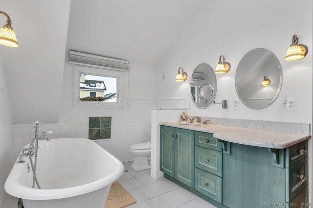 bathroom featuring tile walls, vanity, toilet, a bath, and tile patterned floors