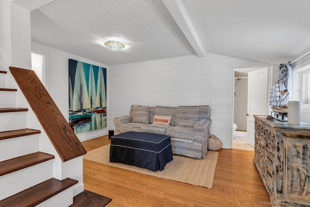 living room featuring wood-type flooring, vaulted ceiling with beams, and wood walls