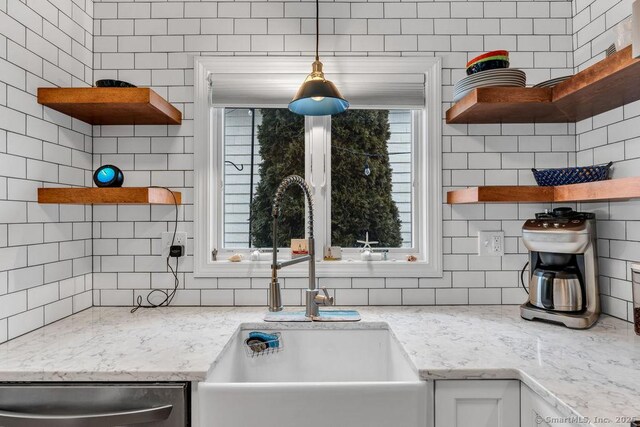 kitchen featuring sink, stainless steel dishwasher, backsplash, and light stone counters