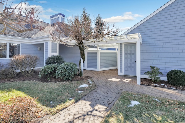 property entrance featuring a yard, a patio area, and a pergola