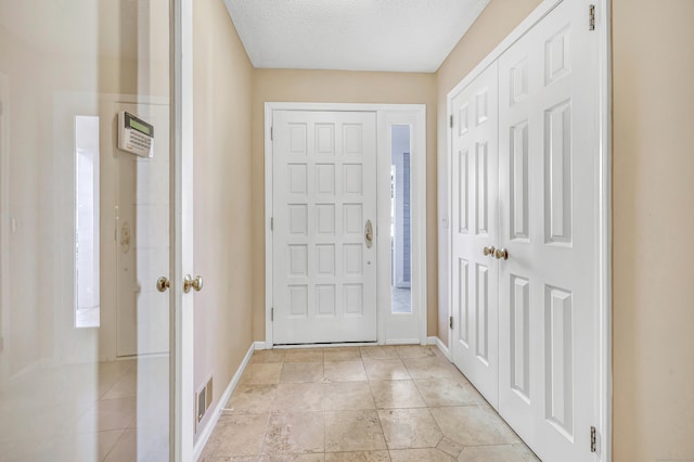 foyer entrance featuring a textured ceiling and light tile patterned flooring