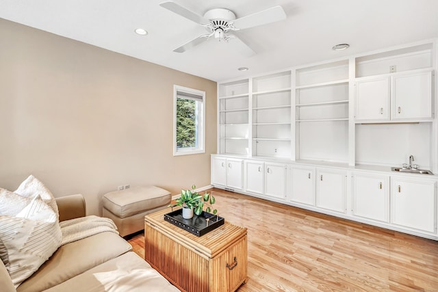 living room featuring sink, built in features, light hardwood / wood-style floors, and ceiling fan