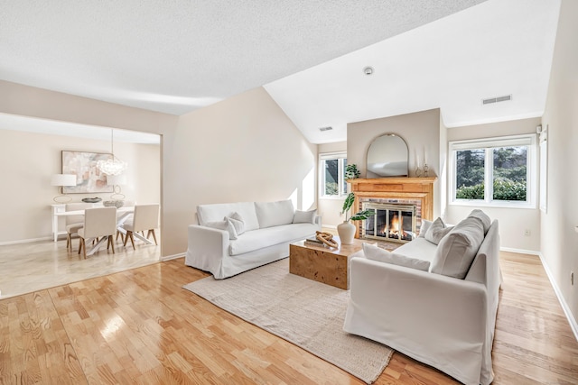 living room featuring a wealth of natural light, a brick fireplace, and light wood-type flooring